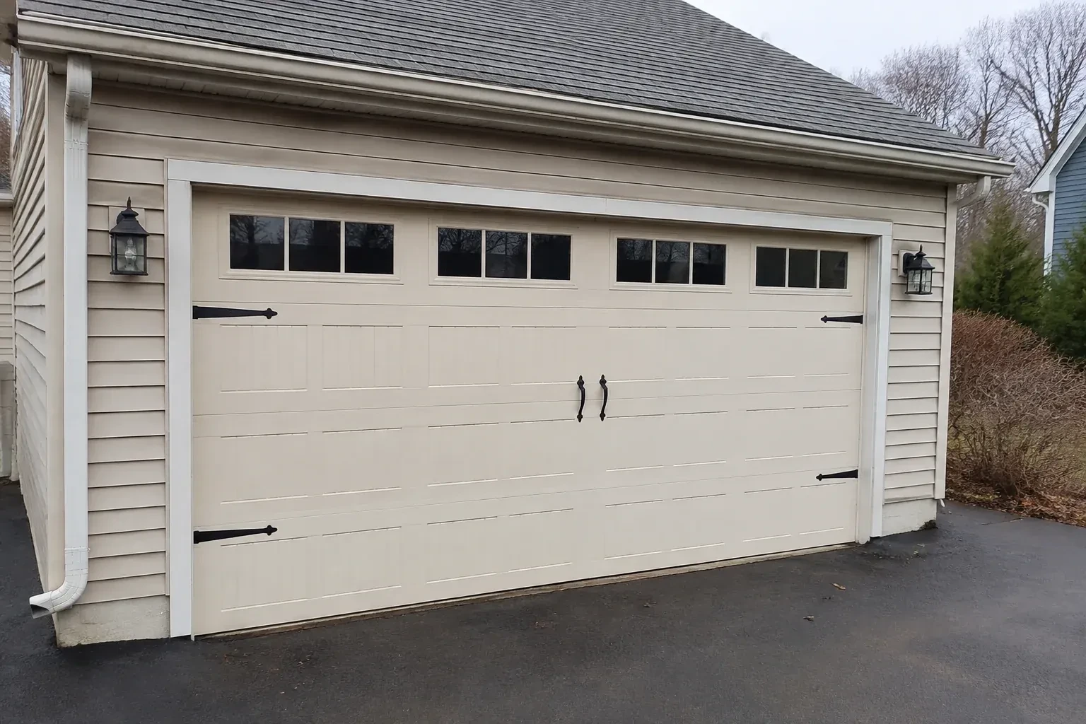 Cream carriage-house-style garage door with dark decorative hardware. — Carriage-House Garage Door Installation, Grimsby